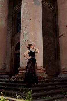 Young attractive woman in the sexy see-through, transparent, transpicuous, diaphanous, clear black dress near the ancient building. Vintage building. Fashion woman. Young woman modern portrait.