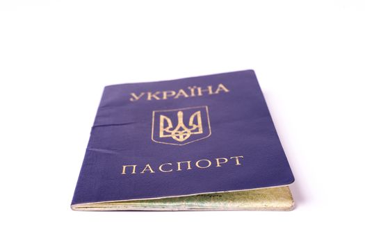 Blue Ukrainian passport isolated on white background. Passport is old and damaged a little bit and closed. Stock photo of travel documents.
