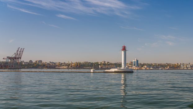 Lighthouse at the entrance to the harbor of the Odessa port, the sea gates of Ukraine in a sunny summer day