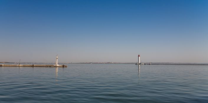 Lighthouse at the entrance to the harbor of the Odessa port, the sea gates of Ukraine in a sunny summer day