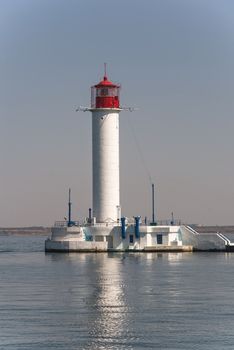 Lighthouse at the entrance to the harbor of the Odessa port, the sea gates of Ukraine in a sunny summer day