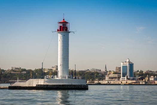 Lighthouse at the entrance to the harbor of the Odessa port, the sea gates of Ukraine in a sunny summer day