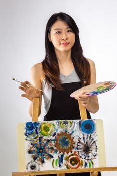 Artist standing behind painting holding palette and brush