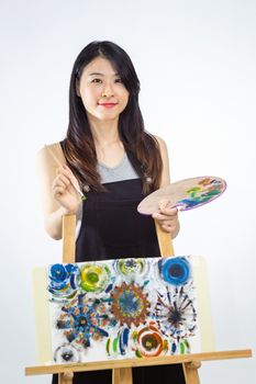 Artist standing behind painting holding palette and brush