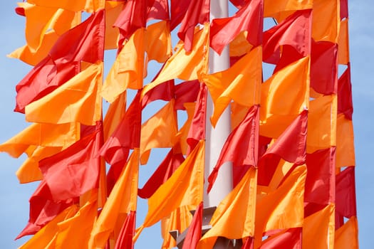 Festive flags of red and orange color on a flagstaff
