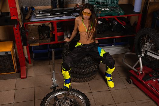 Girl in garage with motorcycle sitting on bike tires