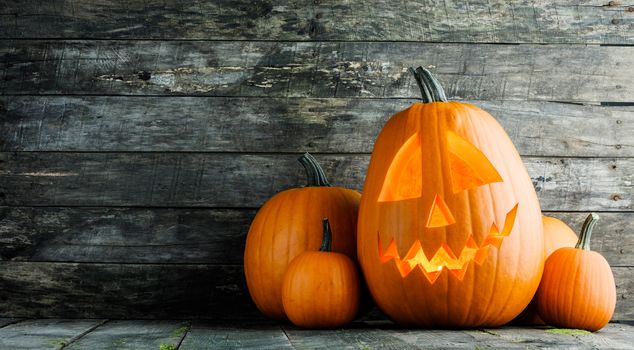 Halloween glowing pumpkin head jack o lantern on gray wooden background