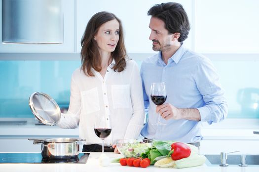 Portrait of a couple having a glass of red wine while cooking dinner of fresh vegetables