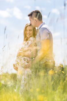 Young happy pregnant couple hugging in nature. Concept of love, relationship, care, marriage, family creation, pregnancy and parenting.