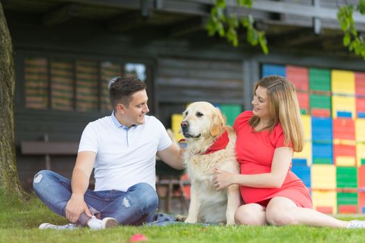 A Young couple expecting baby with their Golden retriever dog.