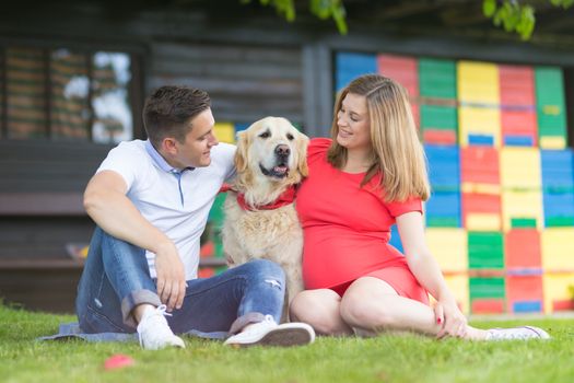 A Young couple expecting baby with their Golden retriever dog.