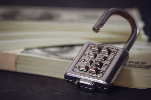 Combination padlock and dollar banknote in darkness. Concept of business secrets or financial security.