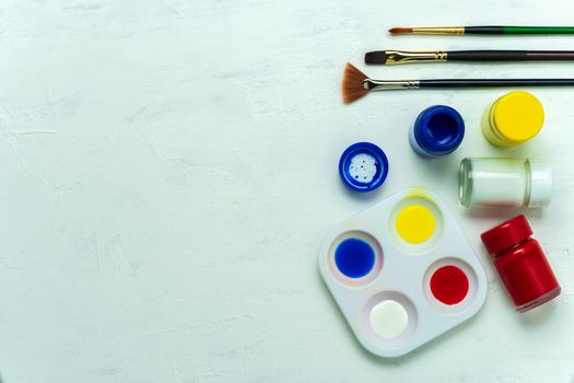 Palette and watercolor with paint brush on white background. Top view and copy space.