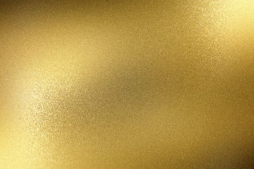 Light shining on rough gold metal panel, abstract texture background
