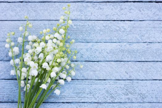 A bouquet of lily of the valley on a wooden background. Spring flowers on a blue wooden background with a place under the inscription