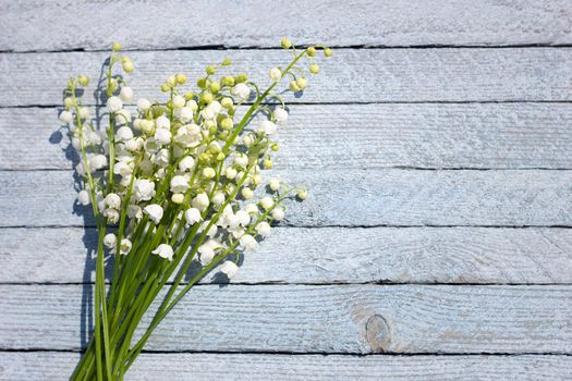 A bouquet of lily of the valley on a wooden background. Spring flowers on a blue wooden background with a place under the inscription