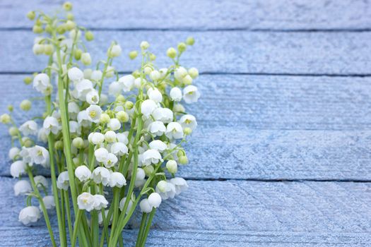 A bouquet of lily of the valley on a wooden background. Spring flowers on a blue wooden background with a place under the inscription