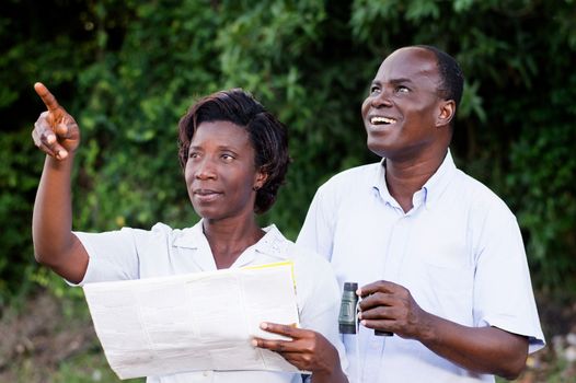 young woman pointing at something the young man looking through binoculars.