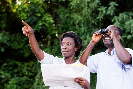 young woman pointing at something the young man looking through binoculars.