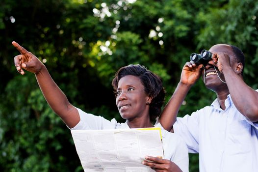 young woman pointing at something the young man looking through binoculars.