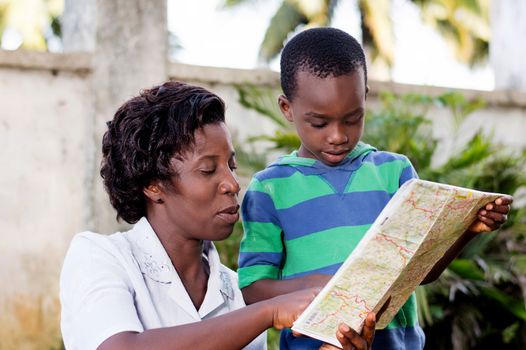 In travel and tourism, a young mother reads a map with her child in the country