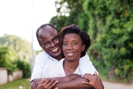 Holiday, happy young couple embracing in the field.