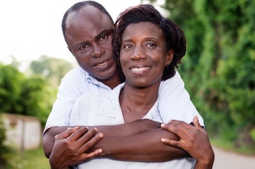 Holiday, happy young couple embracing in the field.