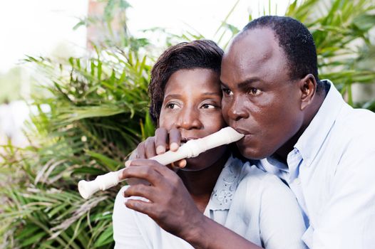adult couple in love sitting by side of a flower, and play the flute.