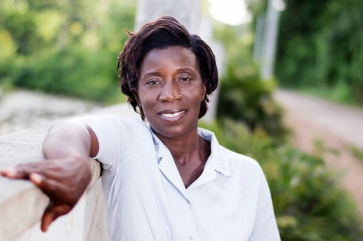 smiling young woman standing by a fence and looking at the camera