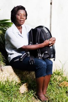 young woman sitting tired, her pack on her knee looking at something.