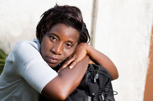 young woman sitting with his head on his bag waiting car.