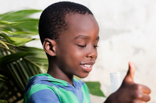 Happy child in a sign of appreciation after drinking a glass of milk.