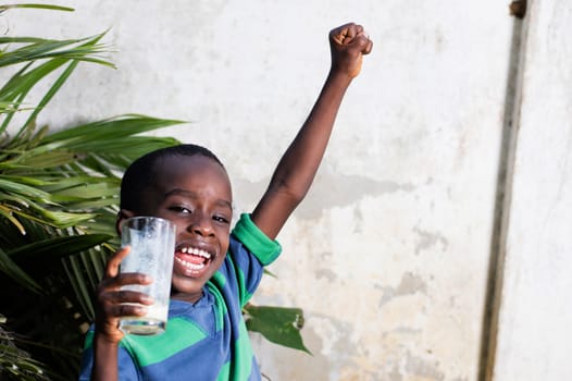 happy child holding a glass of milk manifested his joy, raising his arms.