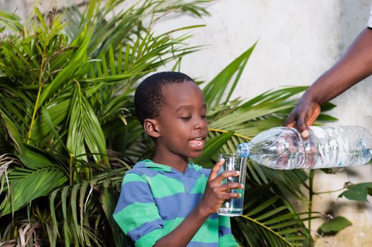 smiling little boy holding a glass of water in which they serve him water.