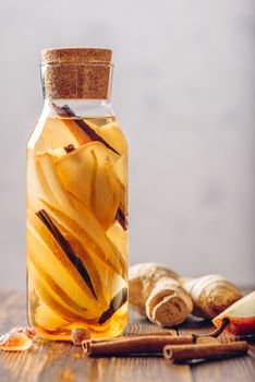 Water Flavored with Pear, Ginger Root and Cinnamon Stick. Some Ingredients on Table. Vertical Orientation and Copy Space.