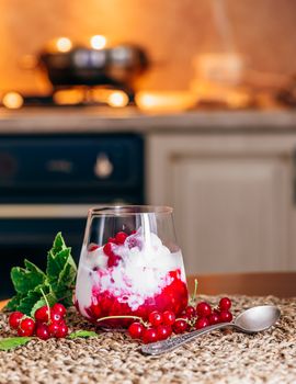 Ice Cream Dessert with Red Currant Jam and Fresh Berries. Kitchen on Background.