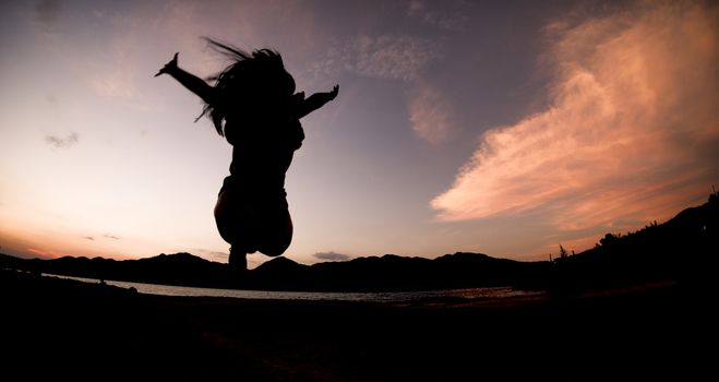 Silhouette, happy jumping Shadow girl Jump on the orange sky in the evening