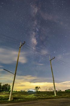 Electric poles in the nighttime countryside, the sky with stars and beautiful taro scenes, clouds below the horizon above the grass