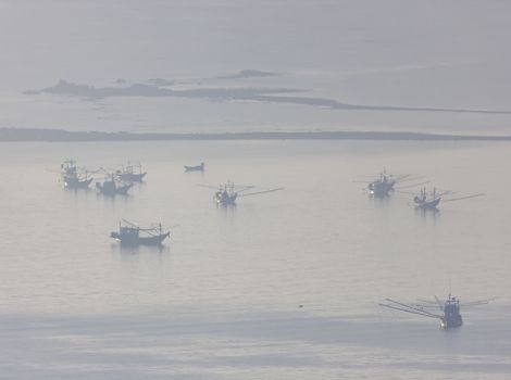Shallow fishing boats anchor at the beach on thick fog days.	