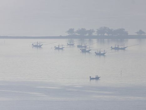 Shallow fishing boats anchor at the beach on thick fog days.	