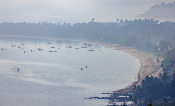 Shallow fishing boats anchor at the beach on thick fog days.	