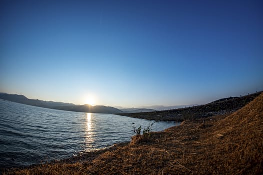 Sunrise at the reservoir, clear blue sky, wide angle from Lens Fisheye, March 9, 2019, Khlong Din Daeng Reservoir, Nakhon Si Thammarat, Thailand