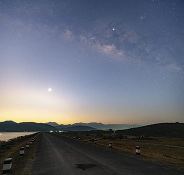 Twilight morning light Before sunrise At the reservoir, straight road ahead over the dam, the Milky Way in the early morning