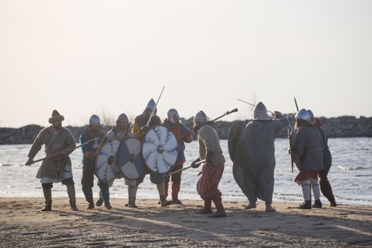 Slavic warriors reenactors with wearpons and shields training fighting outdoors at seaside