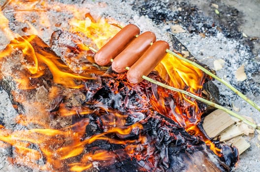 Grilling sausages over an open fire outdoors