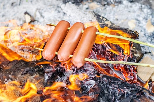 Grilling sausages over an open fire outdoors