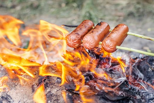 Grilling sausages over an open fire outdoors