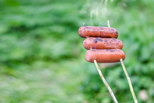 Grilling sausages over an open fire outdoors