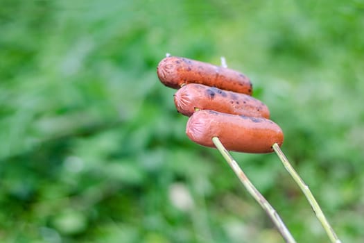 Grilling sausages over an open fire outdoors