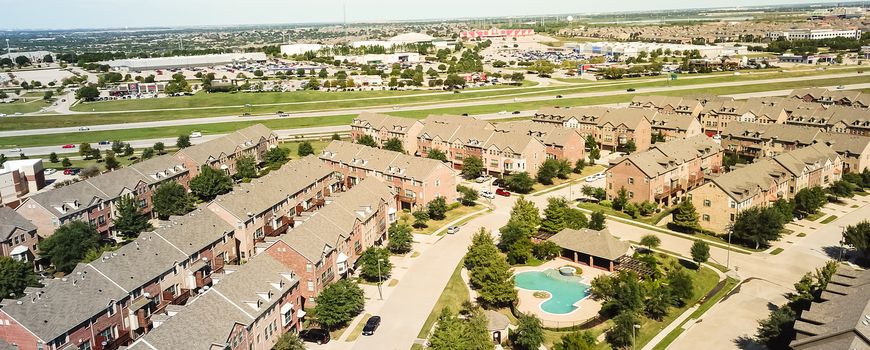 Aerial view apartment building complex with swimming pool near interstate 635 freeway in suburban Dallas, Texas, USA. Opposite are large retail stores and shopping, restaurant destinations